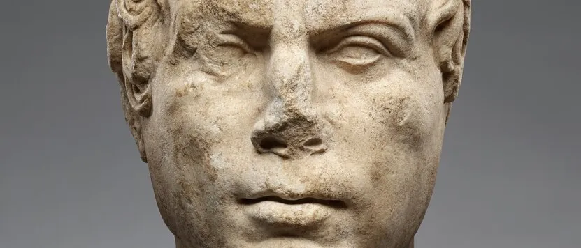 Weathered marble portrait head of a man, Early Roman sculpture, against a grey background