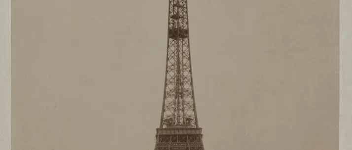 Sepia photograph of the Eiffel Tower at the 1889 Exposition Universelle, domed pavilions at its base, printed title above